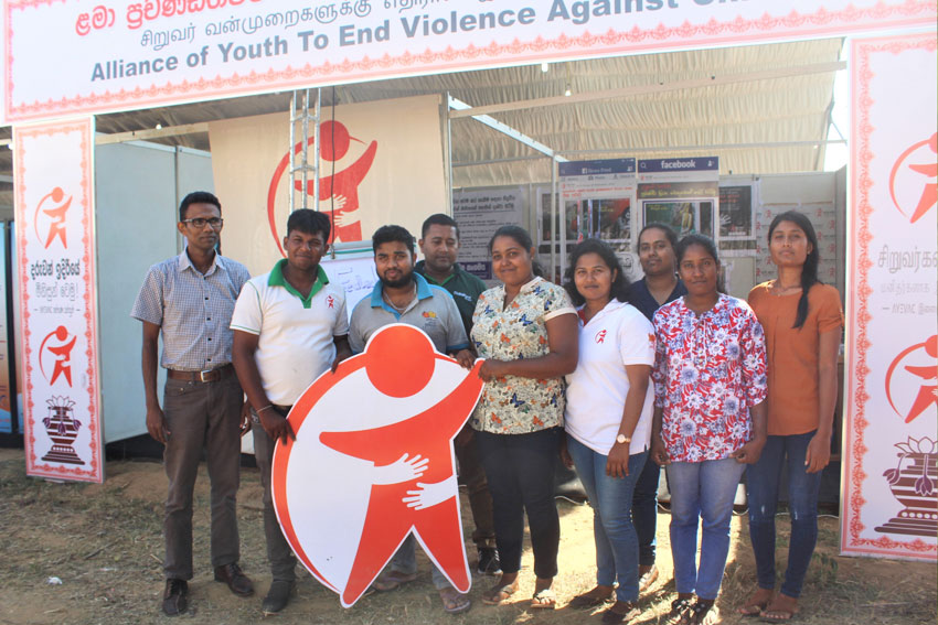 At a ChildFund event booth, Rajitha (far right) poses for a photo with her coworkers at Abhimana Community Development Association.