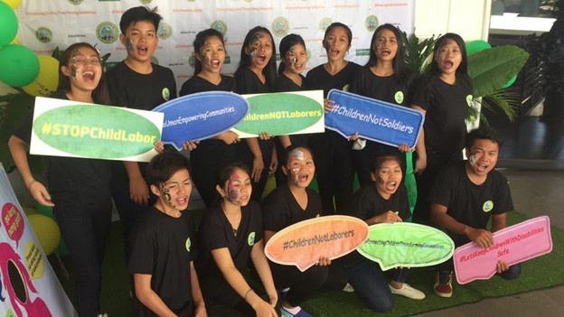 Youth in the Philippines hold up signs about ending child labor.