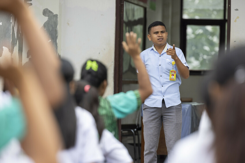 Well-dressed man speaks to a group of students at a school in Indonesia.
