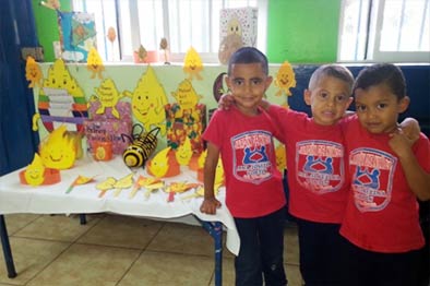 quote three boys in red shirt shirts standing indoors beside table